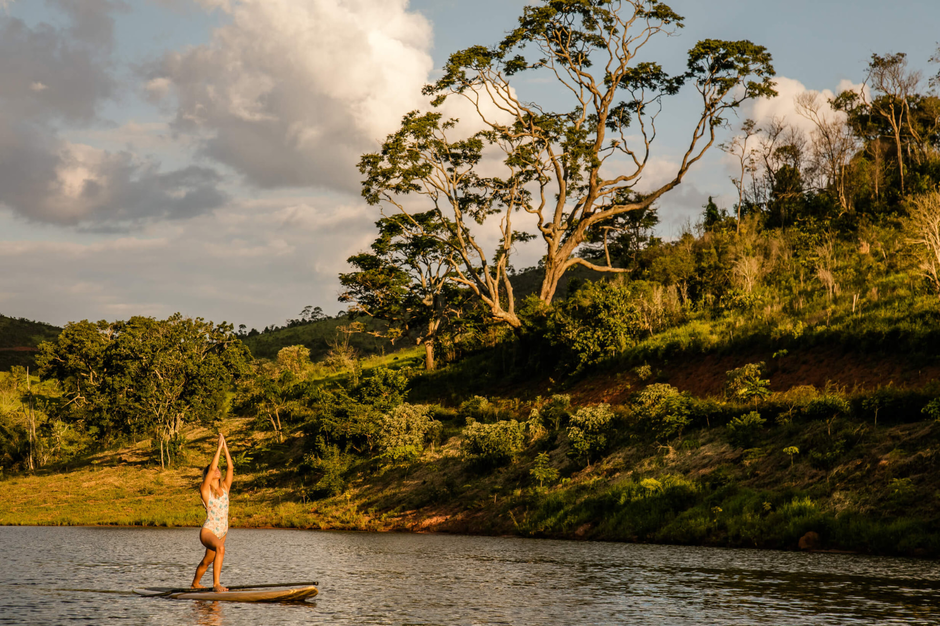 Mulher praticando stand-up paddle ao pôr do sol no Lago Negro, no território do Ibiti Projeto