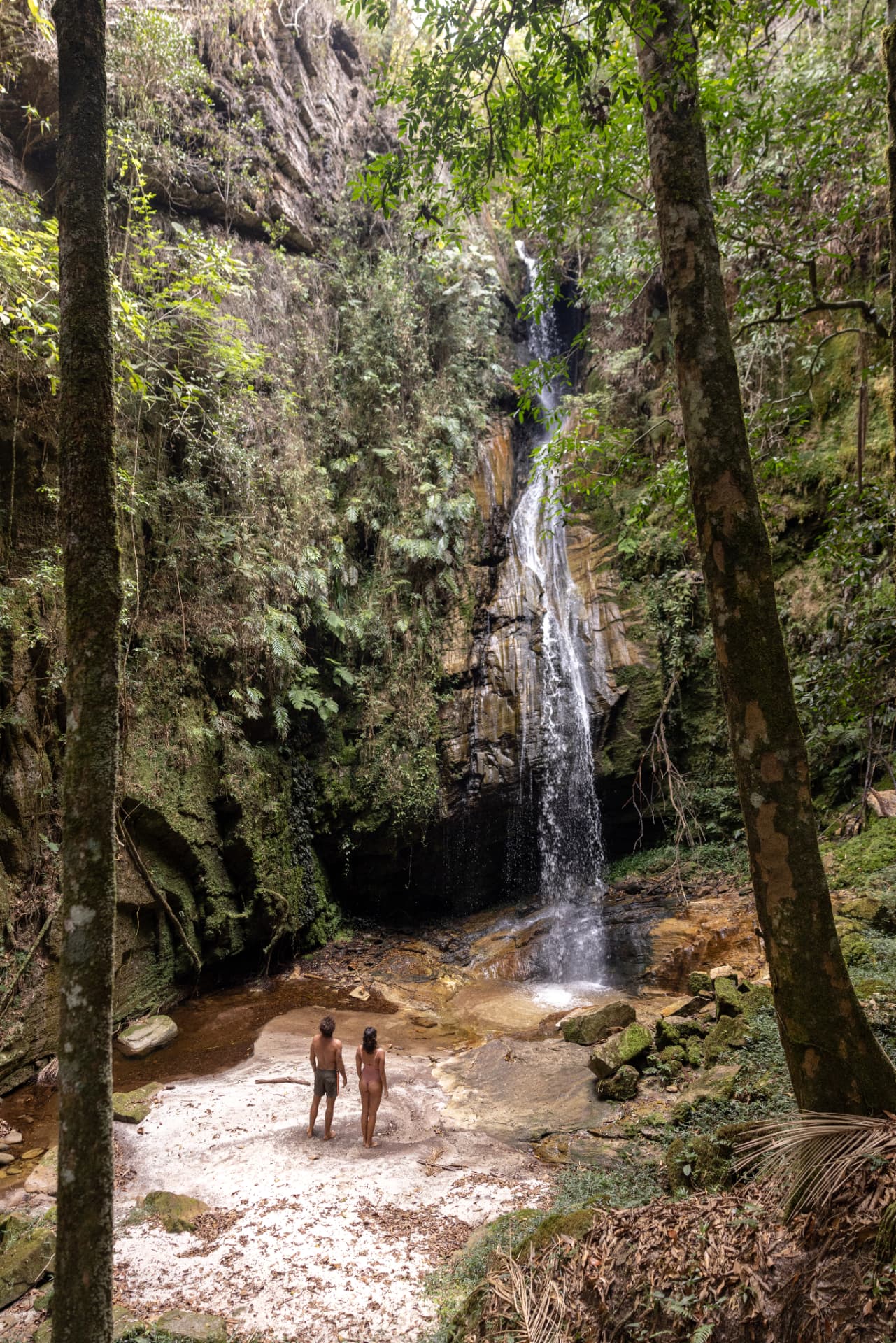 Casal contemplando uma cachoeira em meio à mata da Mantiqueira