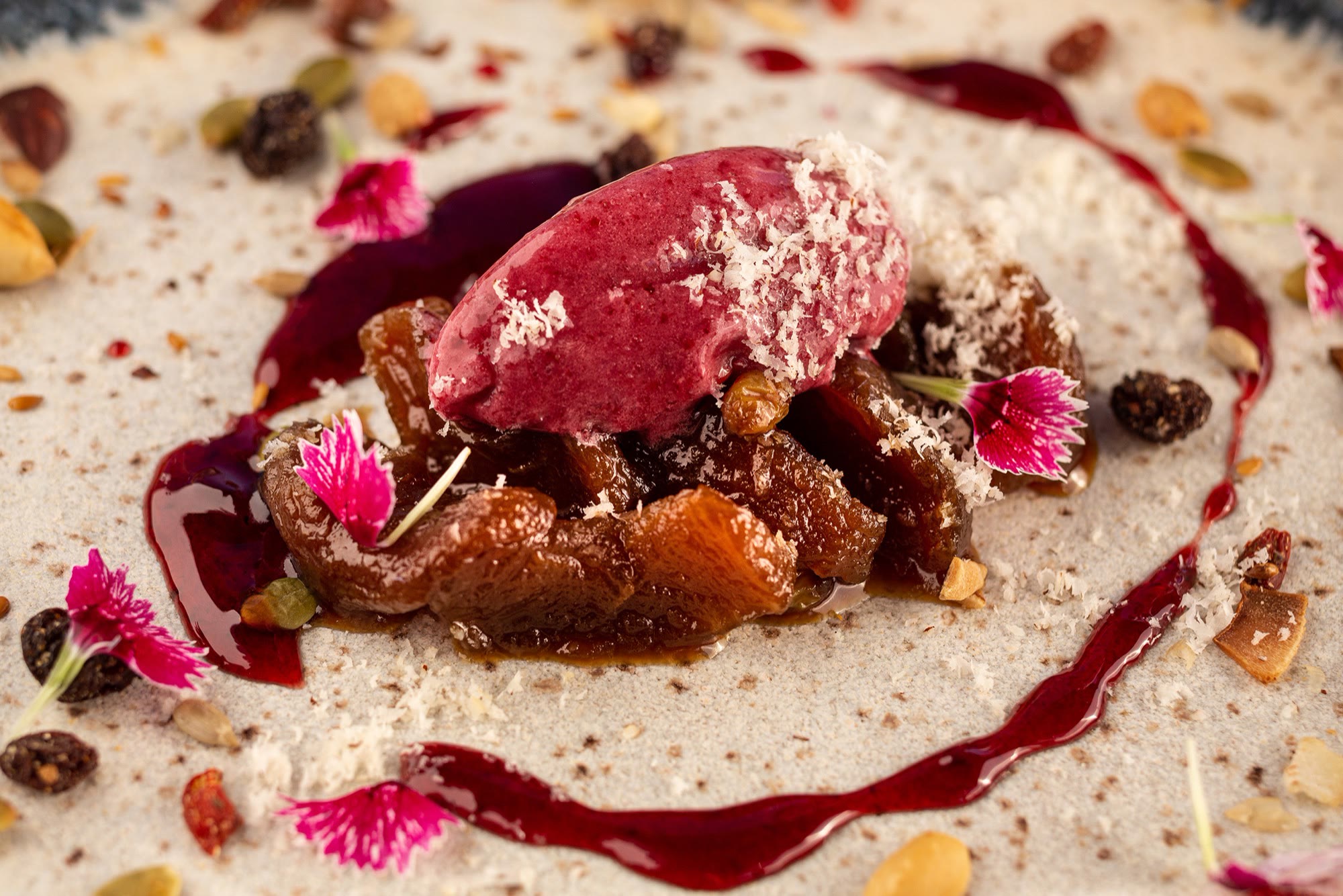 Sorbet de frutas vermelhas sobre frutas caramelizadas, com flores comestíveis e sementes